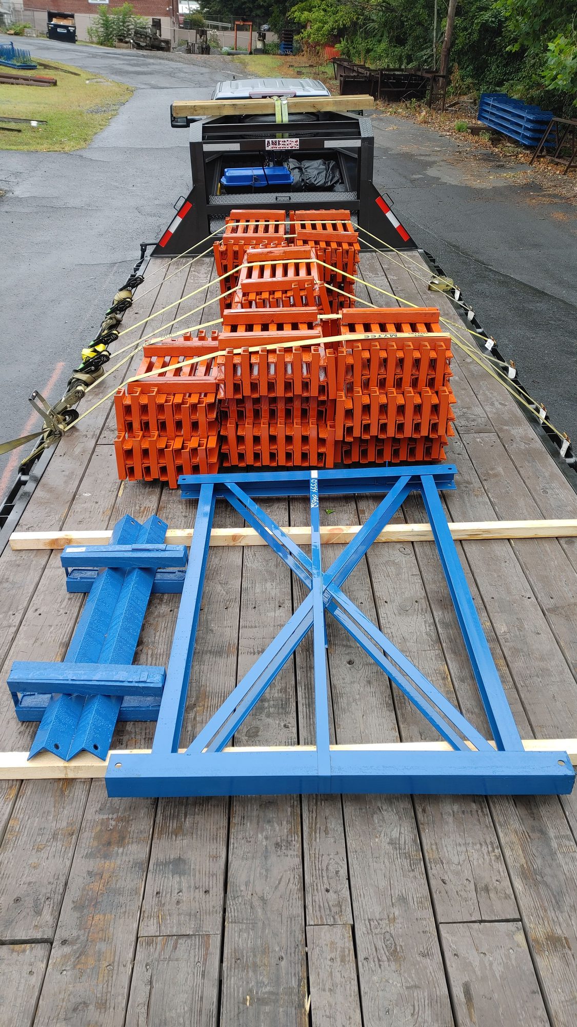 Close view of orange steel brackets and a blue fabricated frame blocked on a trailer deck
