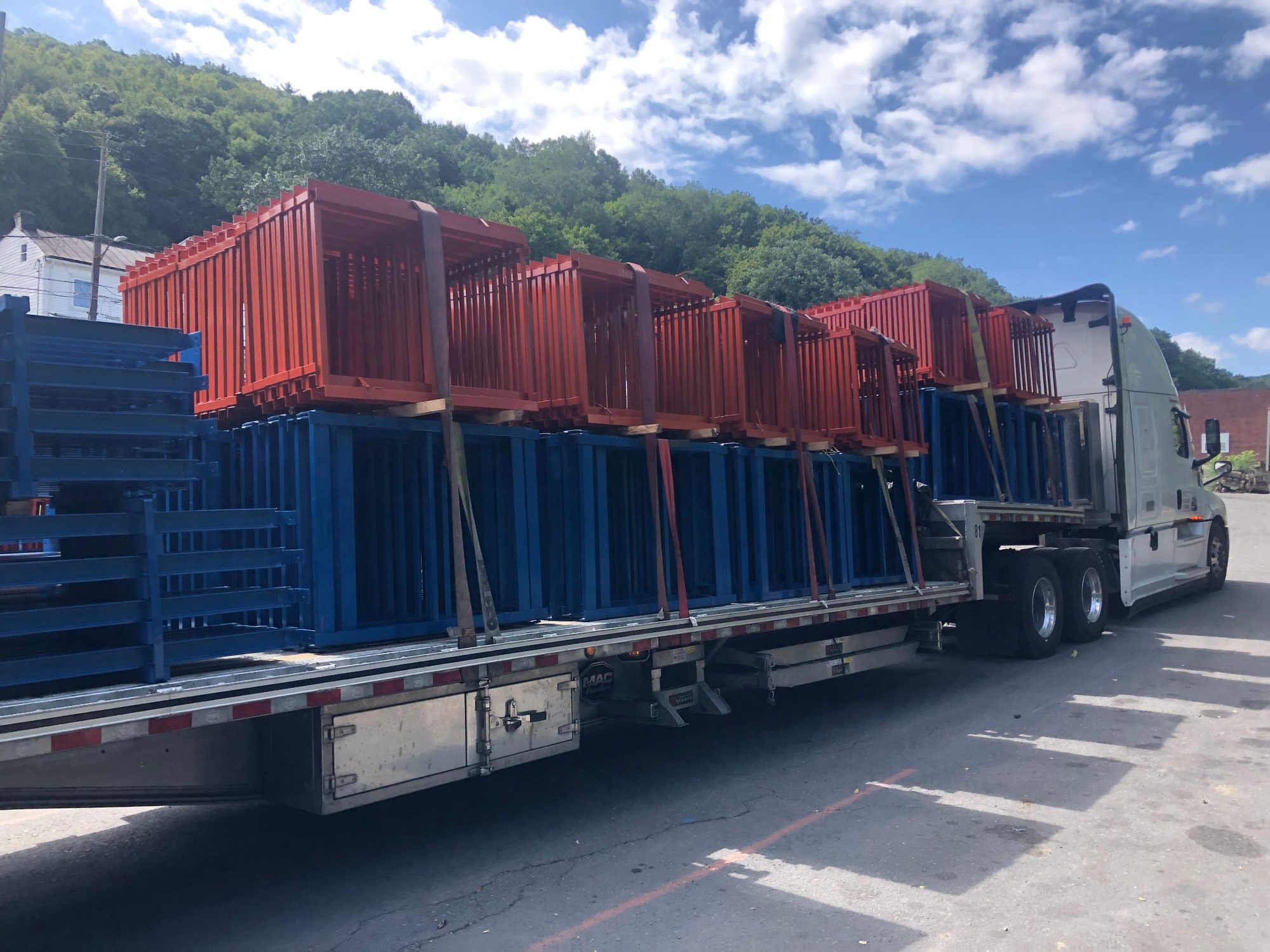 Blue and orange steel frames stacked in tiers on a flatbed trailer