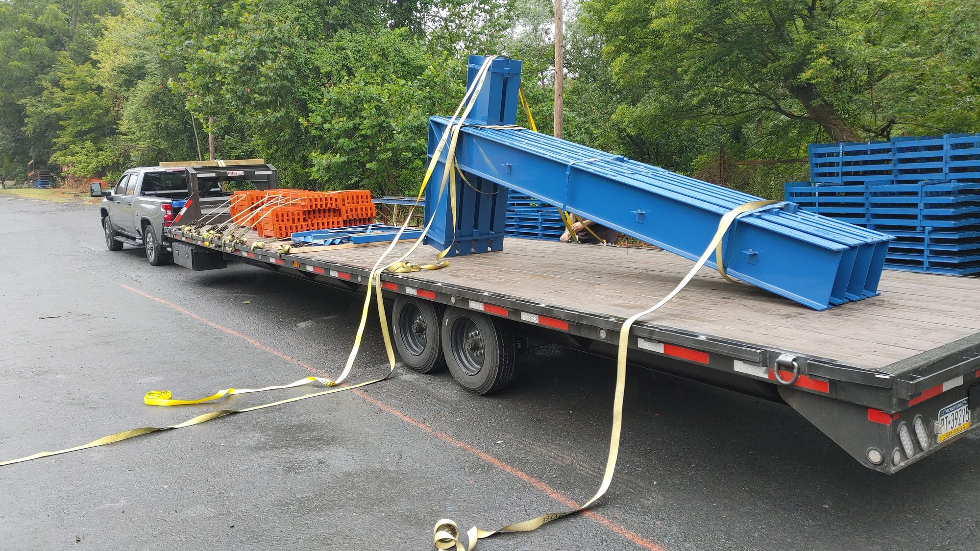 A long fabricated blue steel beam assembly strapped to a gooseneck trailer