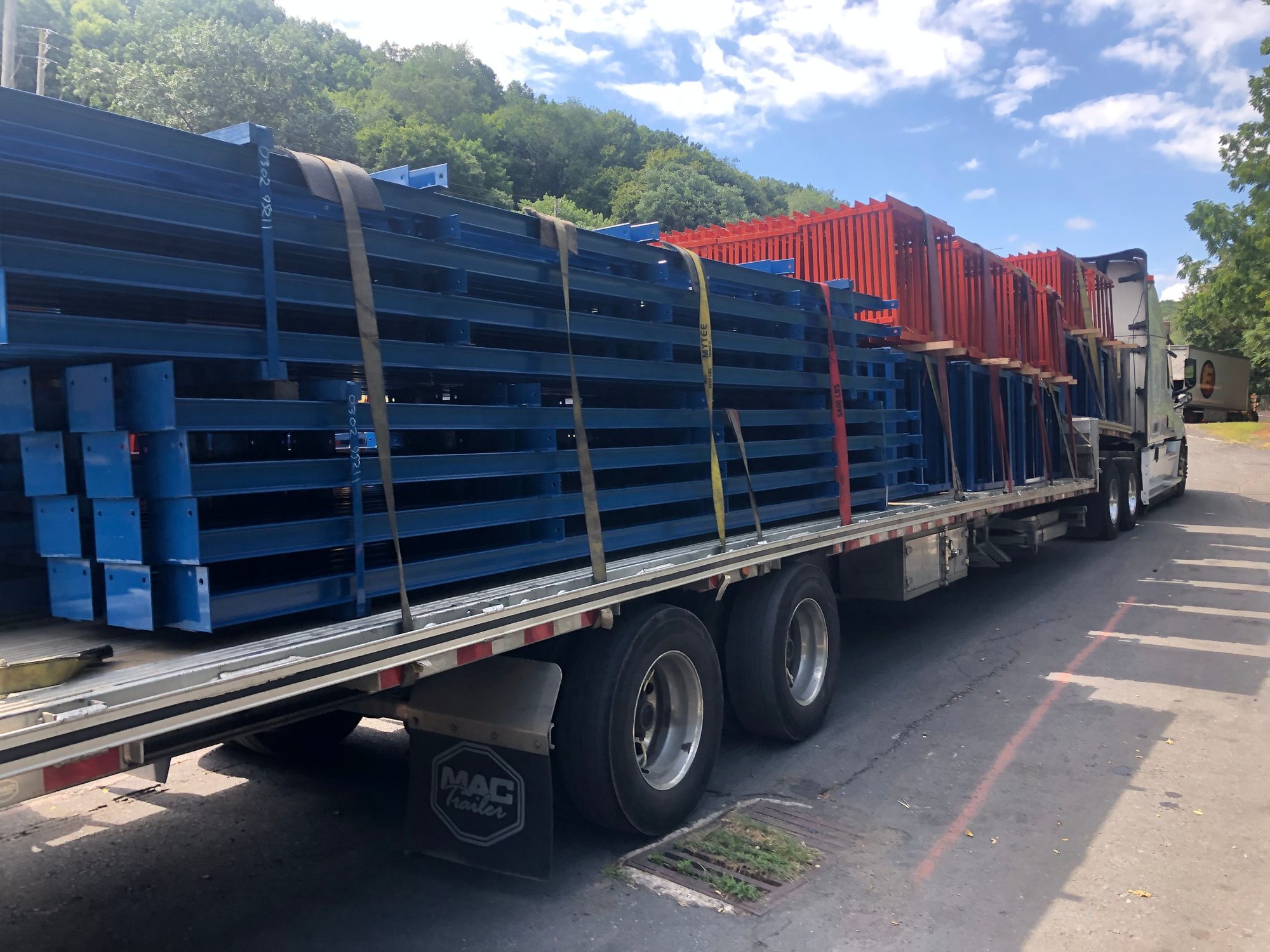 Finished blue and orange steel frames strapped to a flatbed trailer outside Walco Fabricating